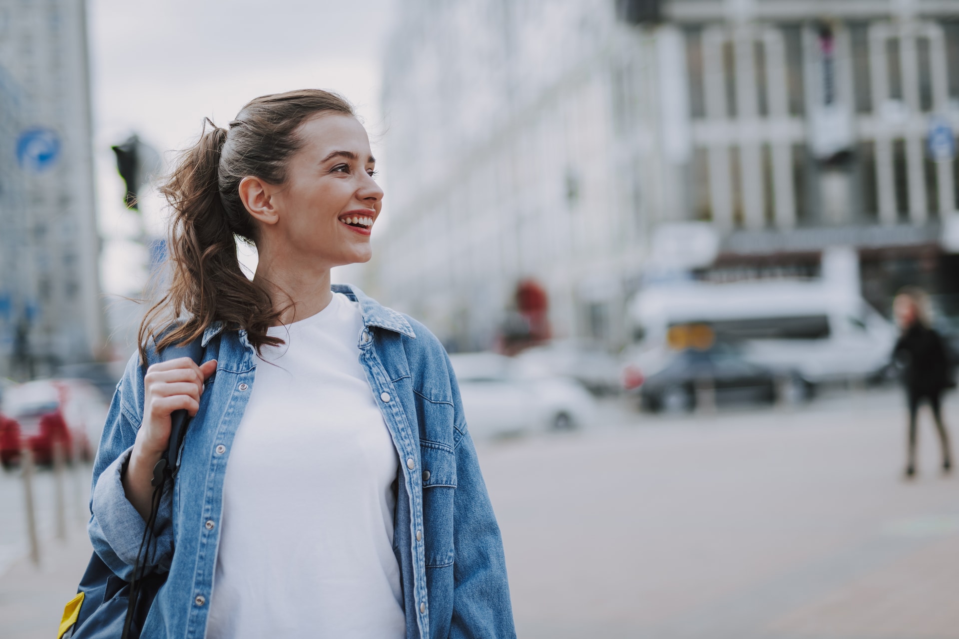 Young woman in a denim jacket smiling outdoors